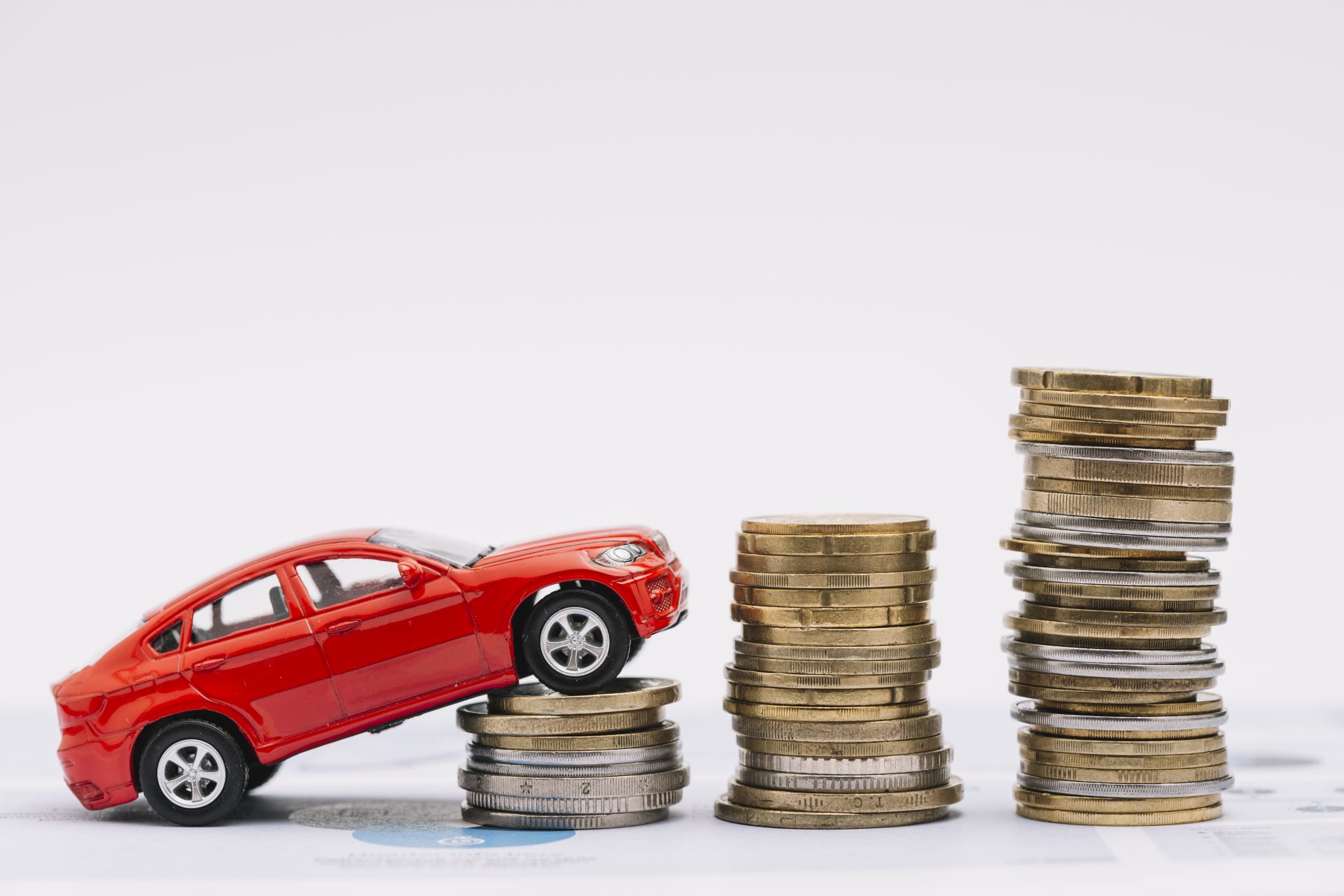 Conceptual image showing a toy car ascending a stack of coins, symbolizing how to save money on car rentals in Dubai